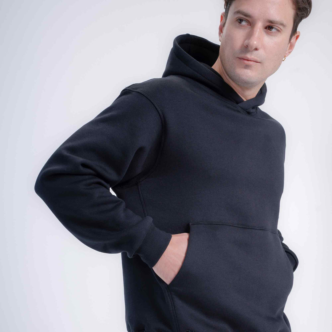 A man wearing black pullover hoodie, shown from the chest up against a light gray studio background.
#color_black