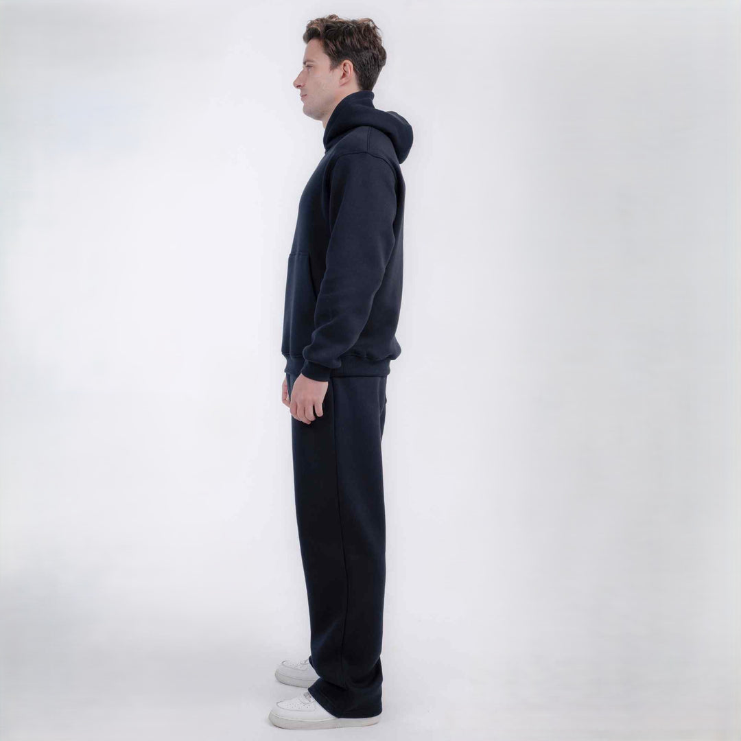 A man in profile wearing a dark navy blue hooded sweatshirt and matching sweatpants, standing against a clean white studio background.
#color_black