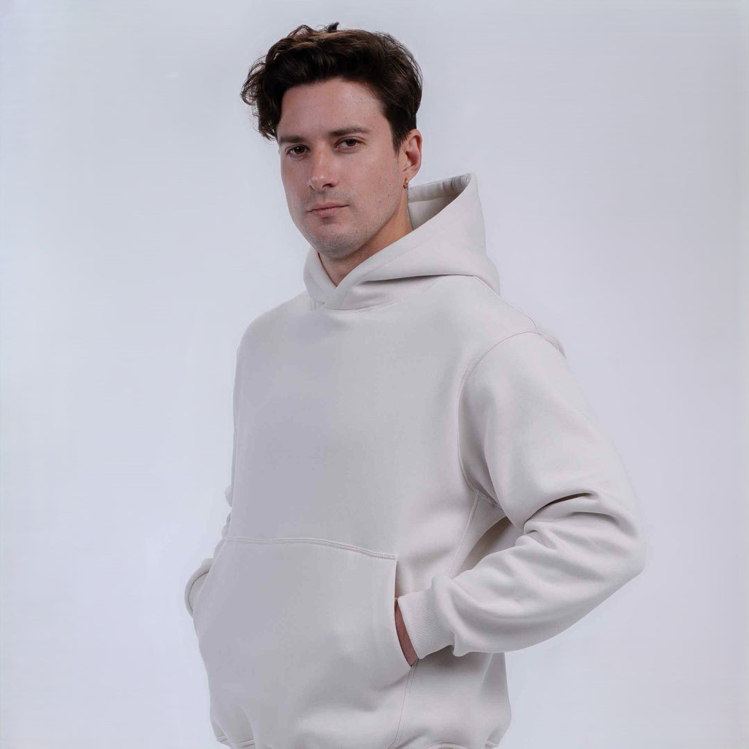A man wearing a light off-white pullover hoodie, standing against a plain light gray studio background.
#color_cloud-dancer