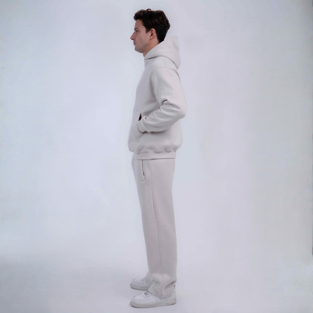 A man in profile wearing a matching light gray sweatshirt and sweatpants set, standing against a plain light gray studio background.
#color_cloud-dancer