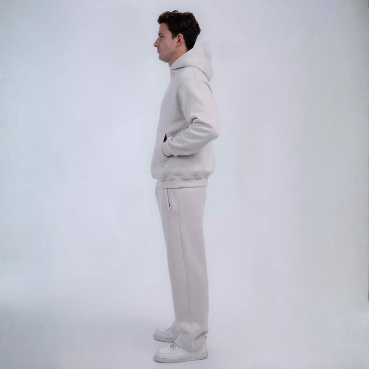 A man in profile wearing a matching light gray sweatshirt and sweatpants set, standing against a plain light gray studio background.
#color_cloud-dancer