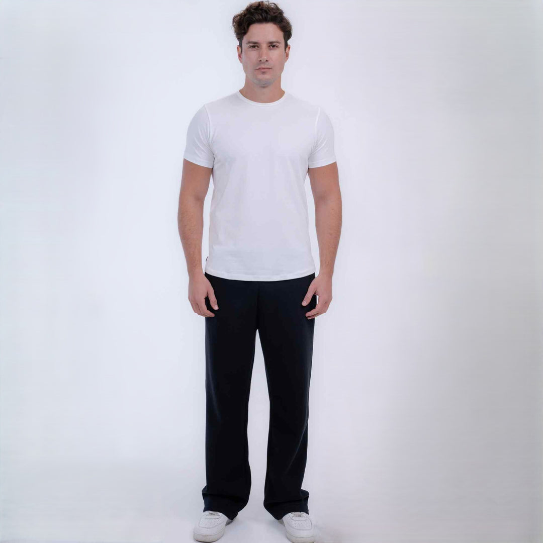 A man modeling a plain white short-sleeve crewneck t-shirt and black pants against a light gray studio 
background.
#color_black
