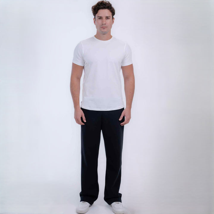 A man modeling a plain white short-sleeve crewneck t-shirt and black pants against a light gray studio 
background.
#color_black