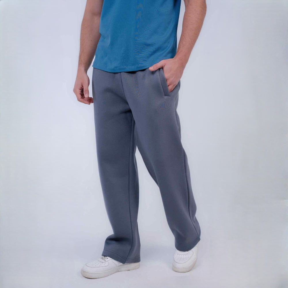 A person wearing gray wide-leg sweatpants, a blue t-shirt, and white sneakers, standing against a light gray studio background.
#color_gray