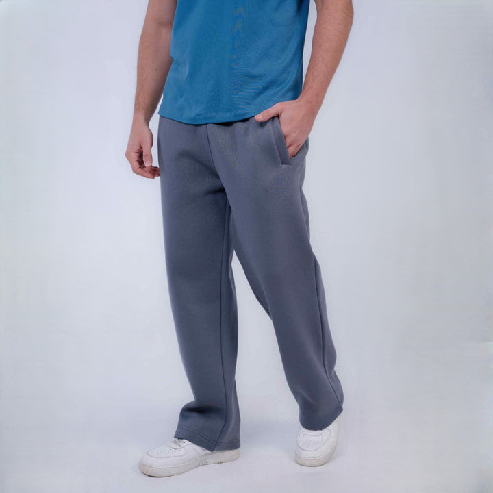 A person wearing gray wide-leg sweatpants, a blue t-shirt, and white sneakers, standing against a light gray studio background.
#color_gray