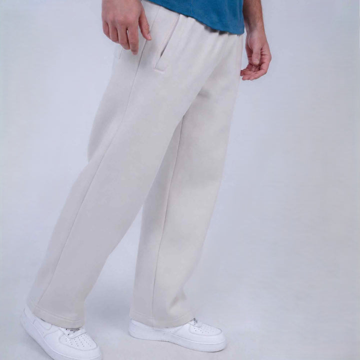 A person wearing off-white wide-leg sweatpants and white sneakers, cropped from the waist down, standing against a light gray studio background.
#color_cloud-dancer
